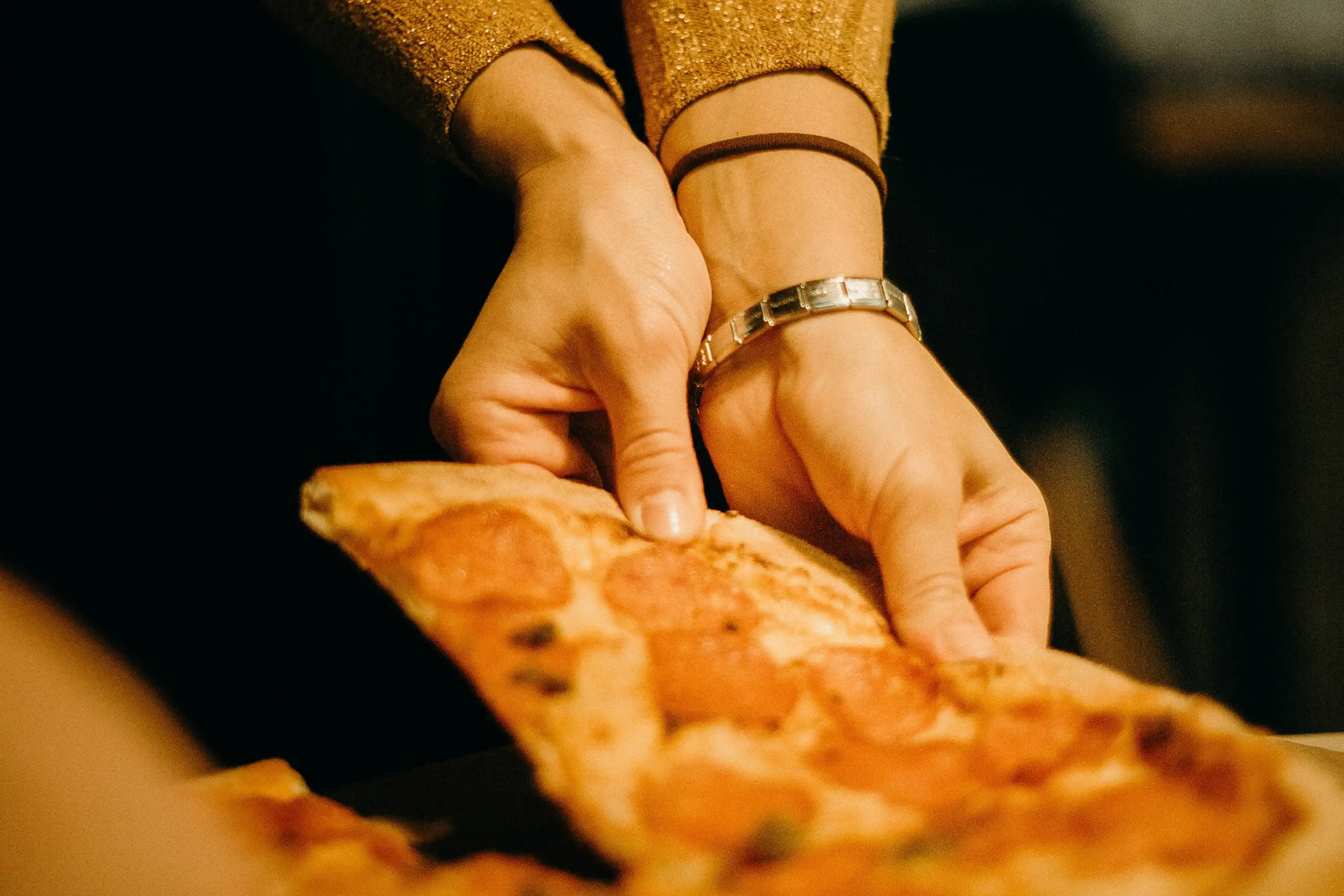 person pulling a piece of pizza